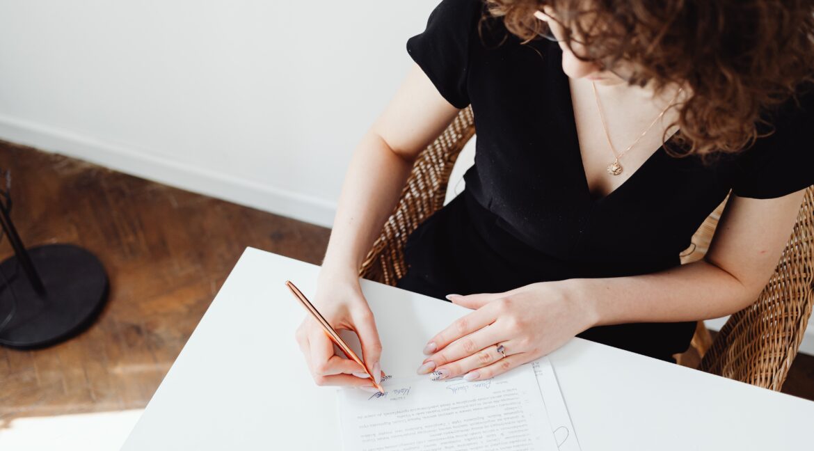 Mulher de preto assinando o contrato de compra e venda do imóvel