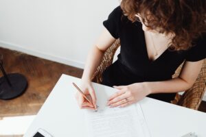 Mulher de preto assinando o contrato de compra e venda do imóvel