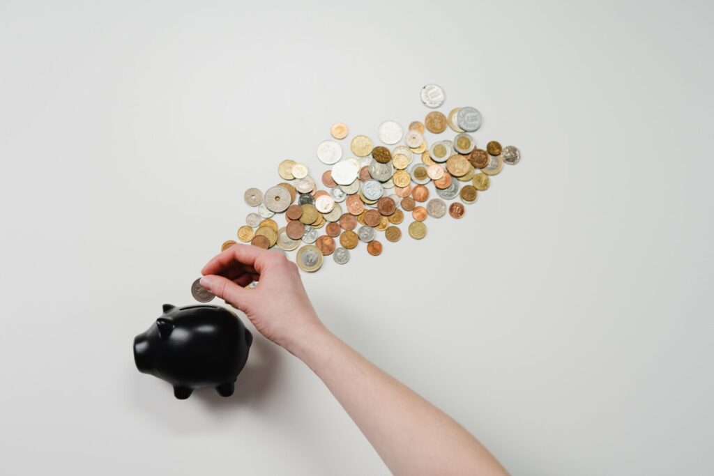 mulher colocando moedas no porquinho para aprender como juntar dinheiro para comprar um imóvel